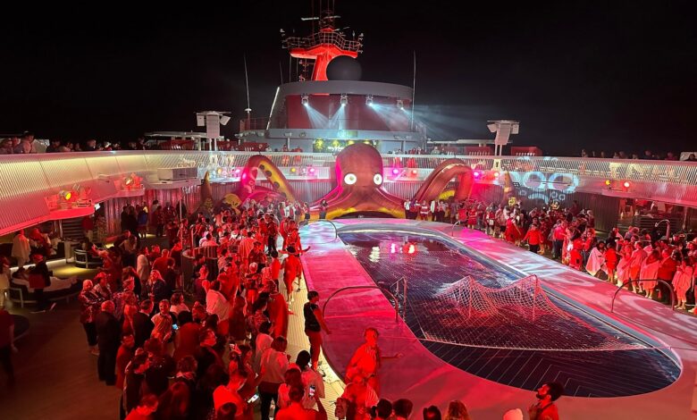 Passengers crowd around the pool for a rave-style Scarlet Night party on Virgin Voyages' Resilient Lady.