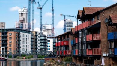 New high rise apartment block towers under construction over older waterfront low rise homes at the heart of London’s Canary Wharf