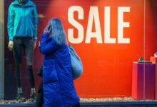 A shopper passes a sale sign in a shop window in Leeds, UK